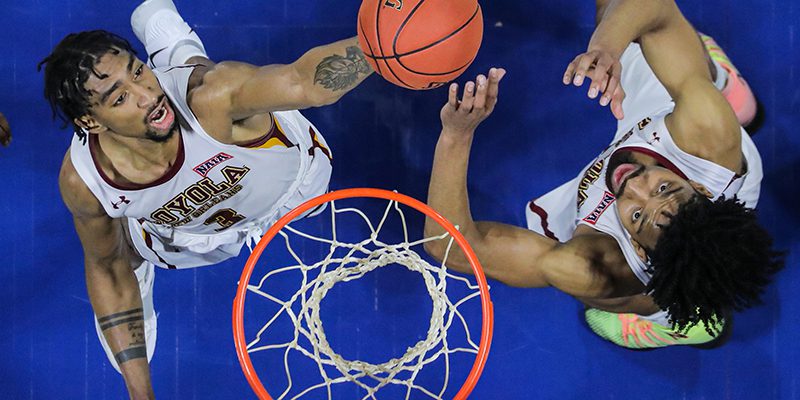 Two basketball players chasing a ball