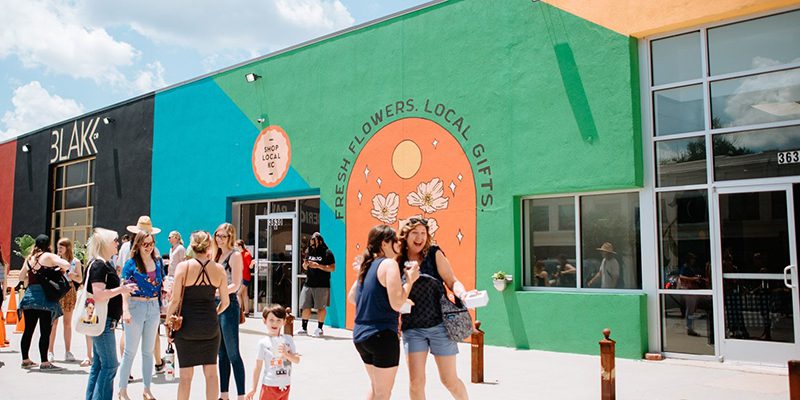 Exterior of Shop Local KC painted in blue, green, and yellow with shoppers in front
